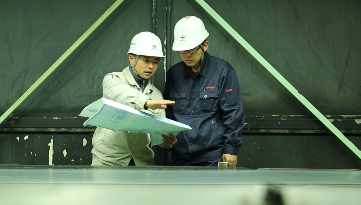 李超（左）在車間與同事交流工作。    鞍山鋼鐵黨委宣傳部供圖